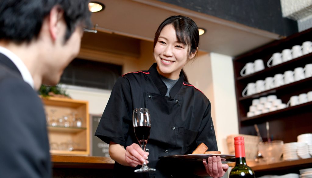 ワインをスーツを着た男性に提供するお盆を持った女性