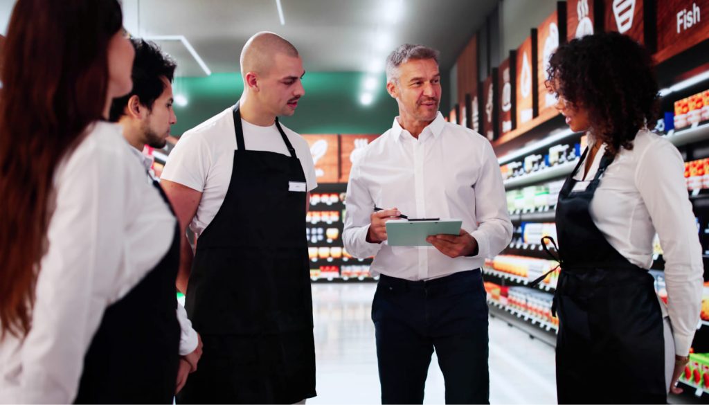 エプロンをきた従業員をまとめるスーツを着た男性