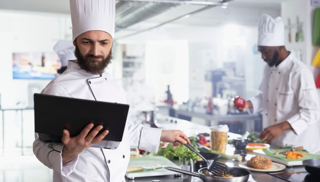 タブレットを操作しながら料理をする男性シェフ