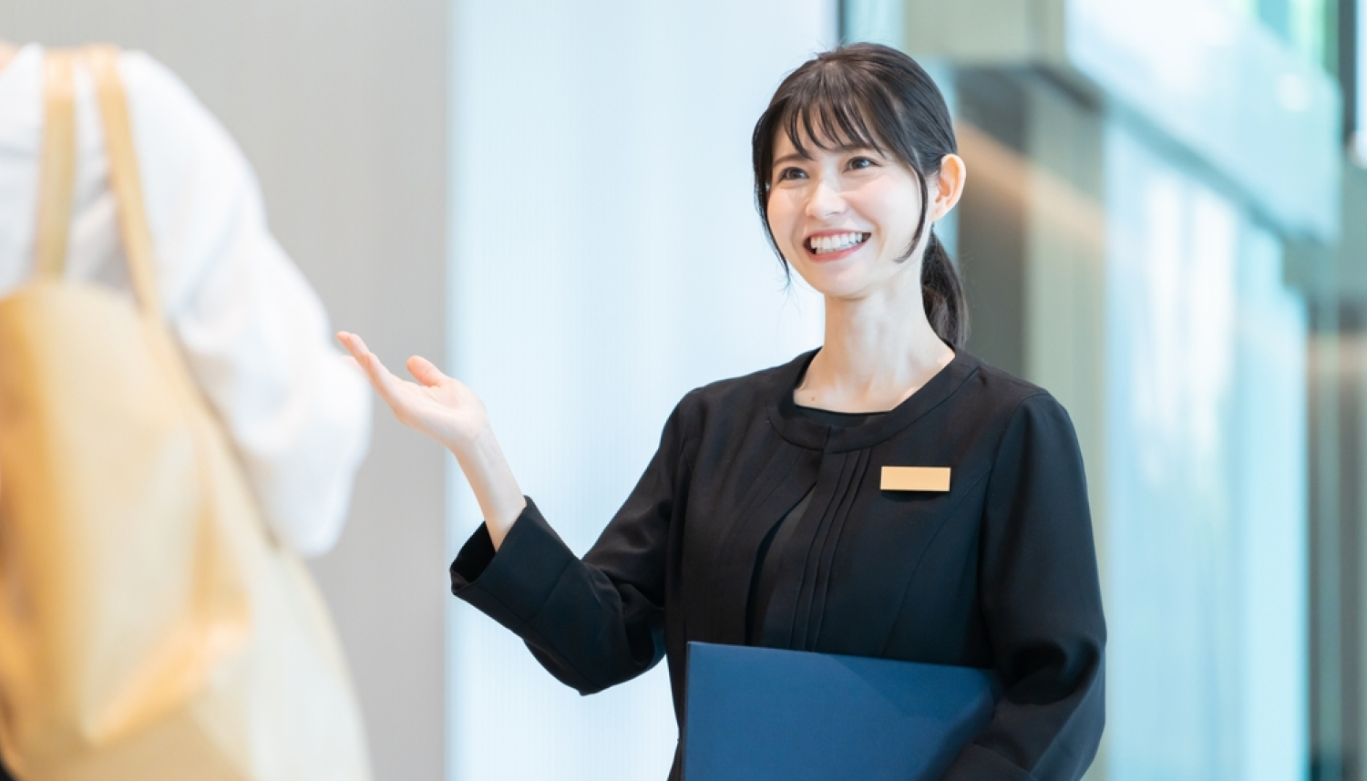 黒い服を着た女性が右手をあげて道案内している