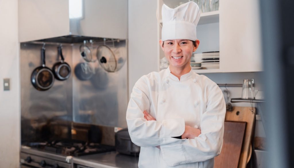 厨房で腕を組んでいるシェフのアジア人男性