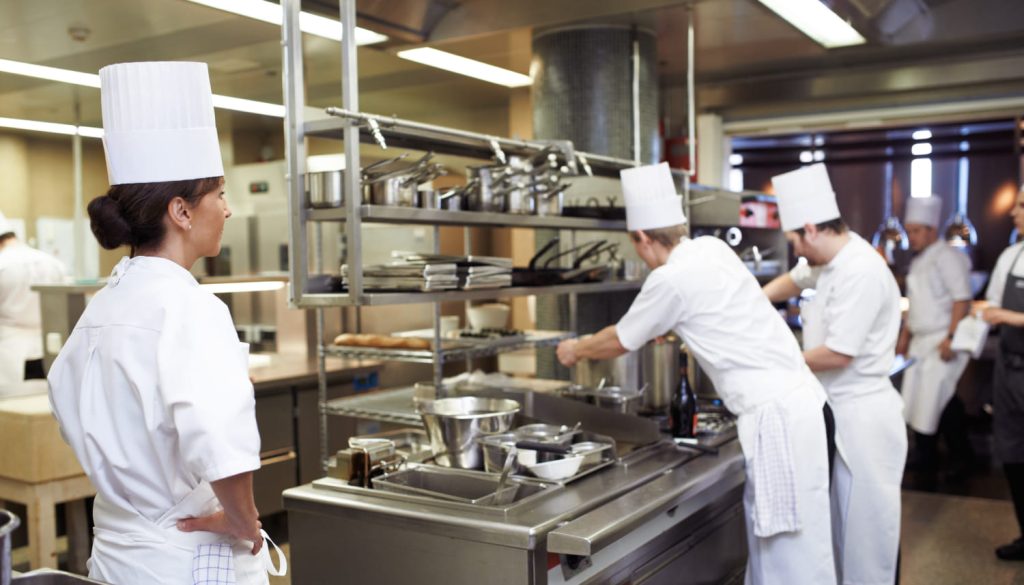 厨房の料理人たちを見守るシェフ