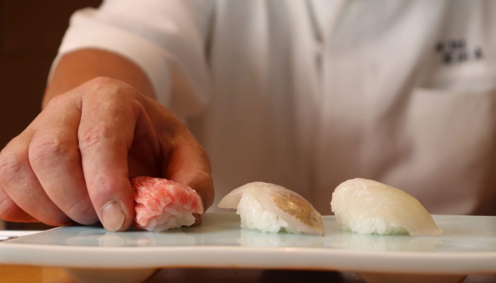 マグロの寿司をお皿に置いている手元の写真