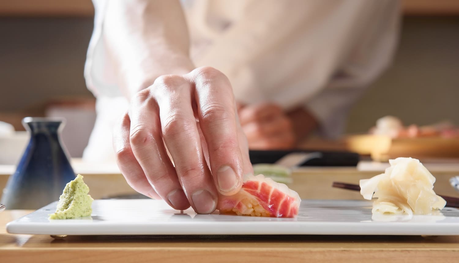 赤身の寿司をお皿に置く寿司職人の手