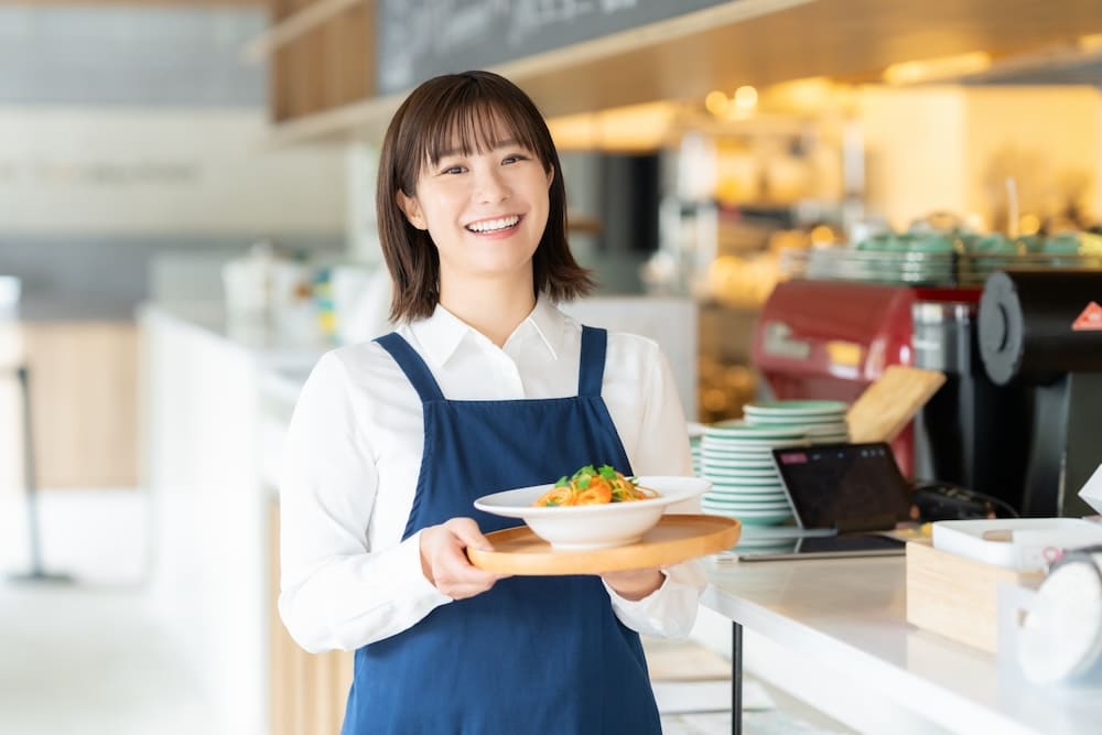 料理を運ぶエプロンをかけた女性