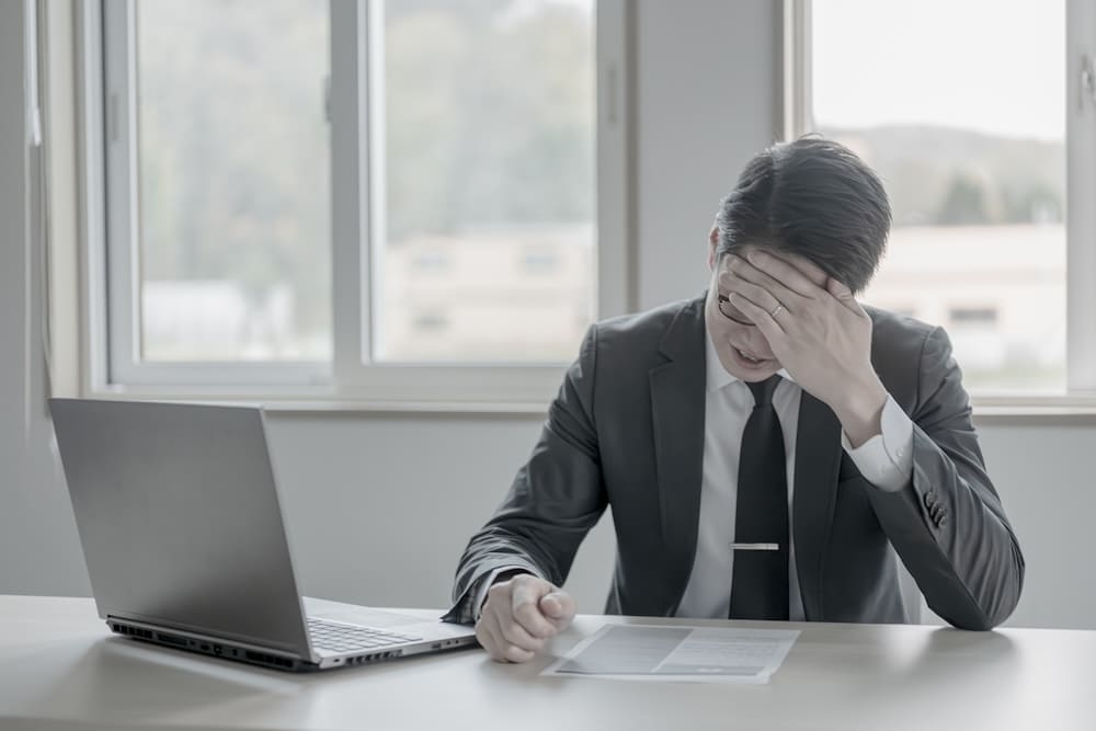 頭を悩ませるサラリーマンの男性