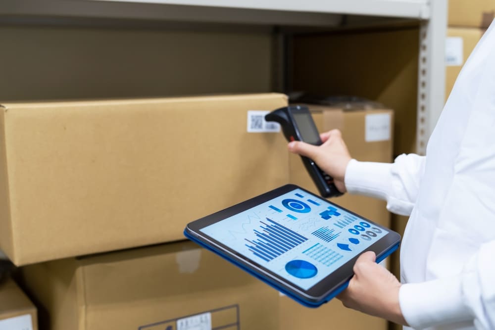 ダンボールのバーコードを調べる従業員と手元のタブレット