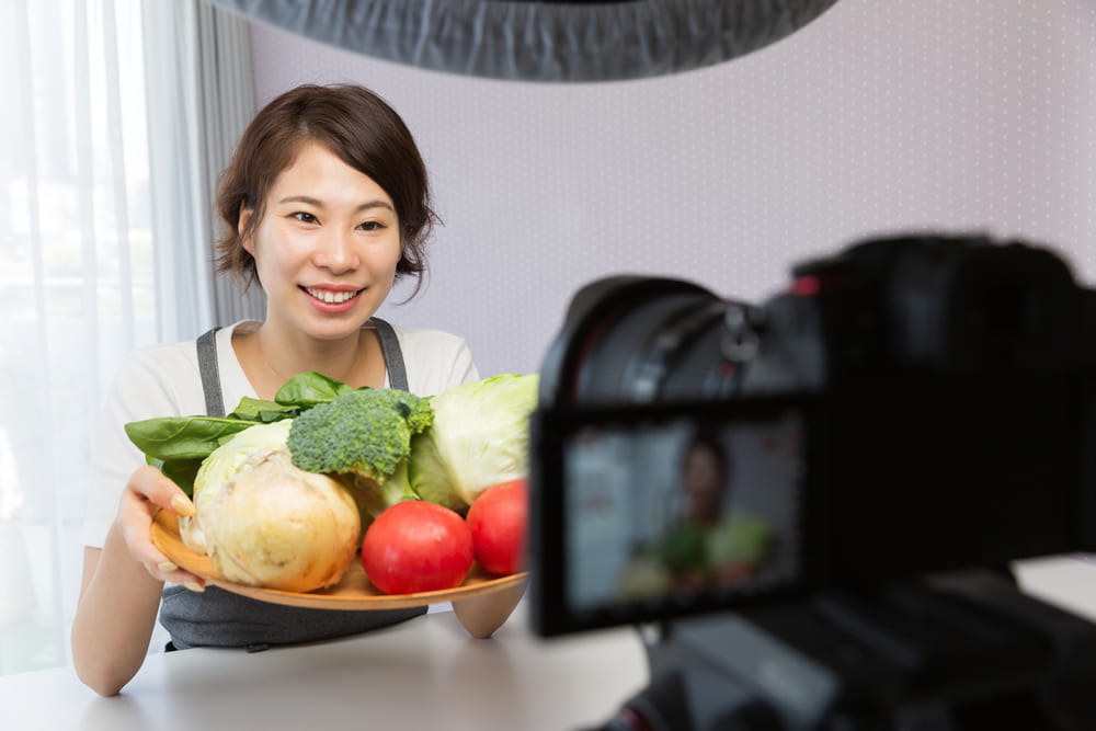 動画を撮りながら野菜をカメラに向ける女性