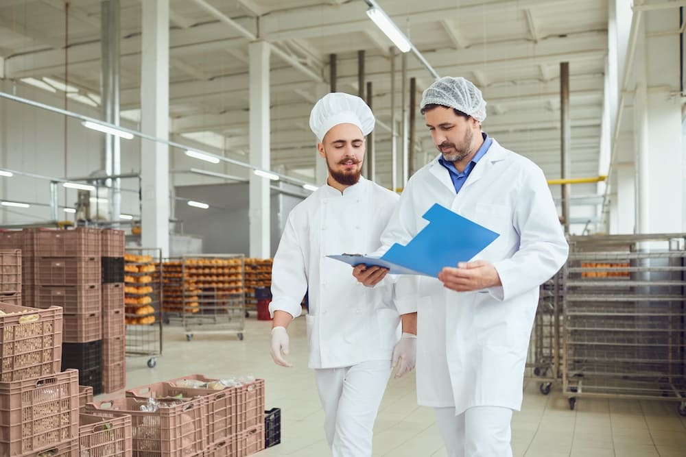 倉庫で書類を見ながら打ち合わせをする2人の男性作業員