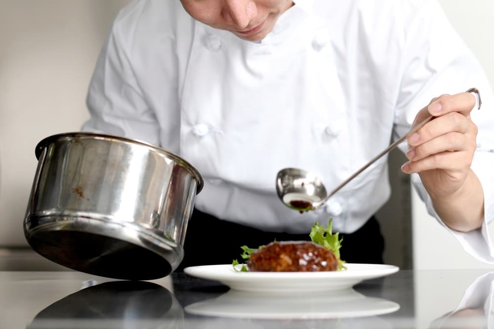ハンバーグにソースを盛り付ける男性シェフ