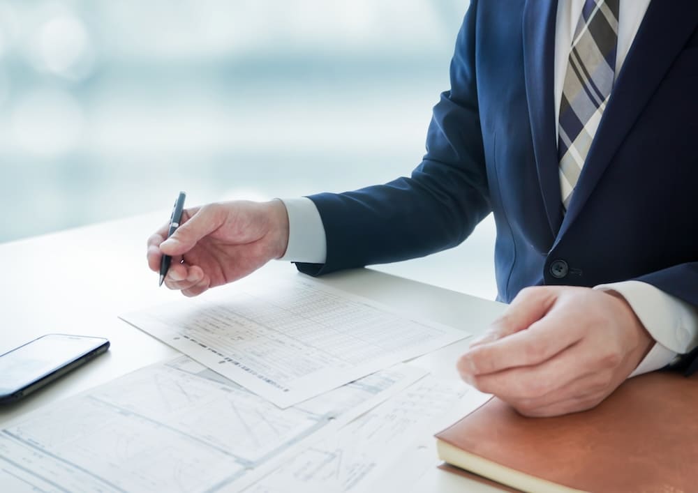 スーツを着た男性とテーブルに広がった書類