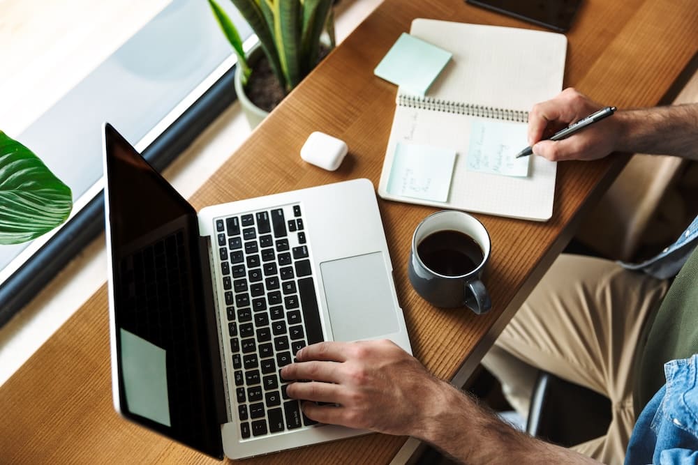 パソコンを操作しながらメモを取る男性