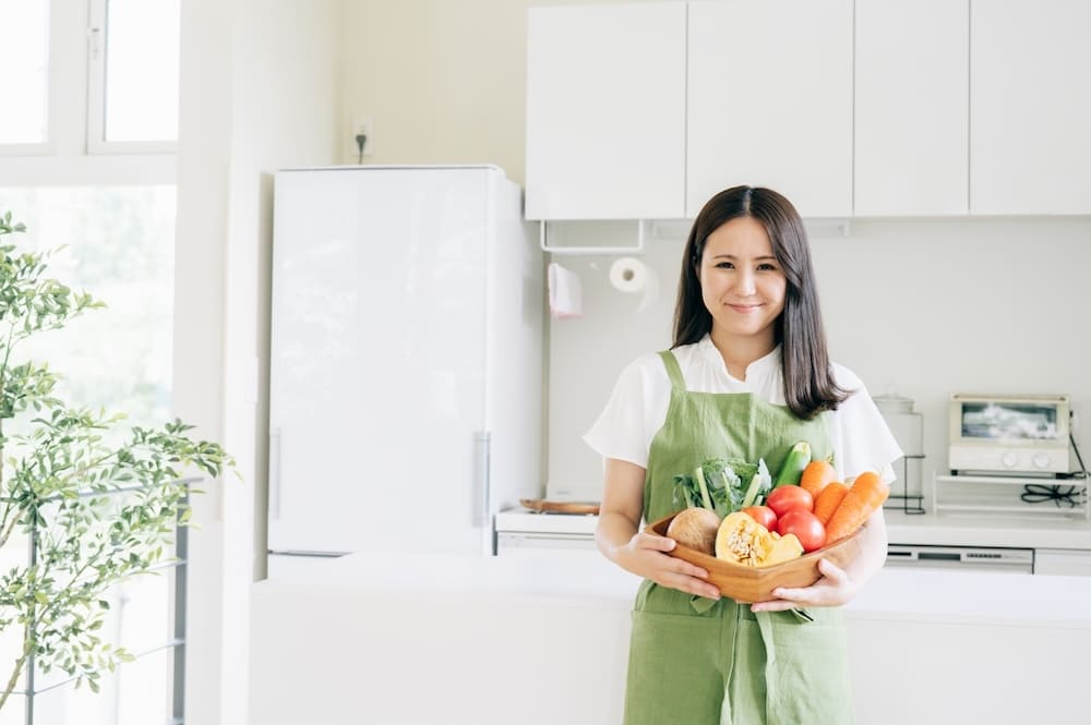 複数の野菜を持った女性