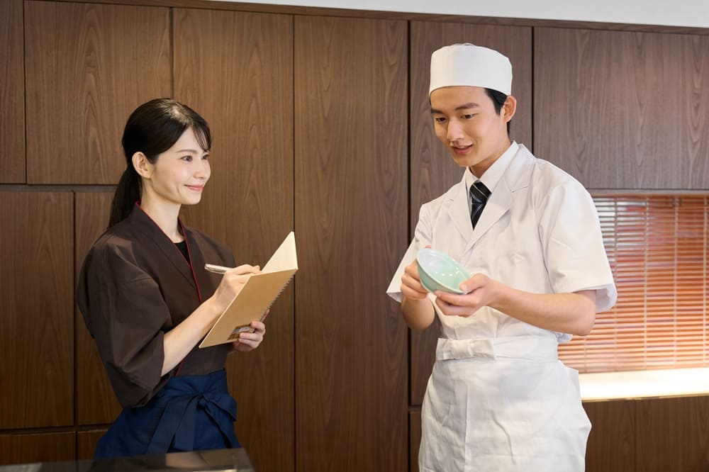 打ち合わせをする和食の男性料理人と従業員の女性