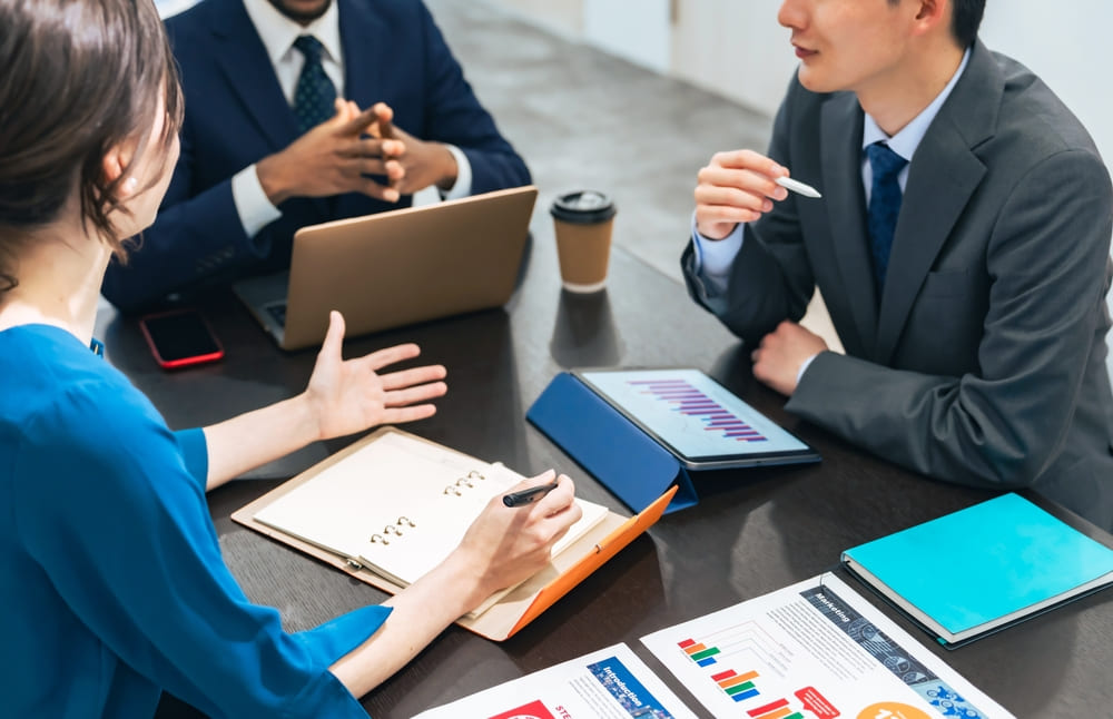 タブレットとパソコンで打ち合わせをする男性と女性の社会人