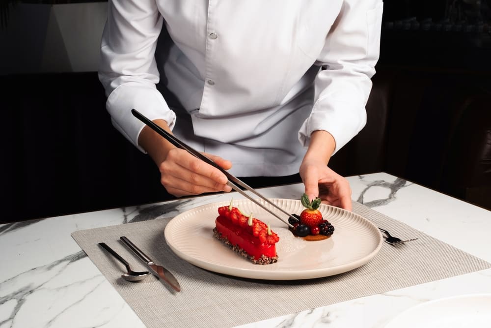 いちごやラズベリーをケーキに盛り付ける女性パティシエ