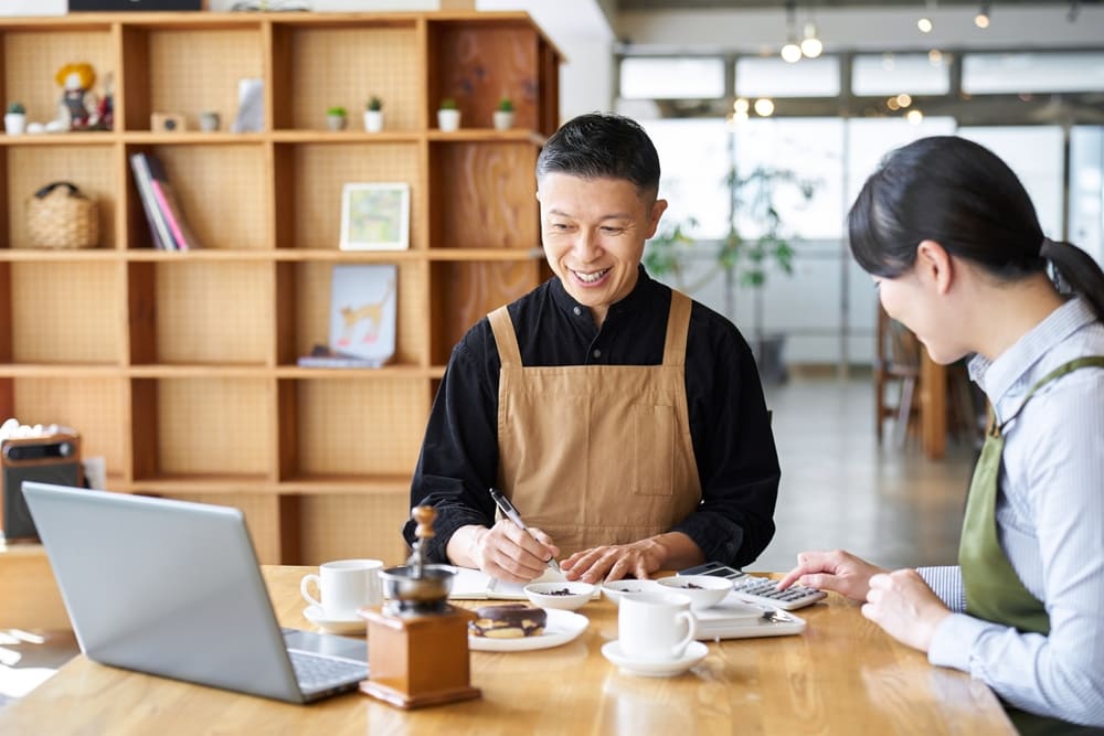 パソコンを使って内容をメモする男性と女性店員