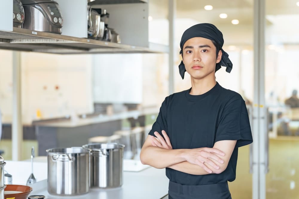 腕を組んだ若い男性料理人