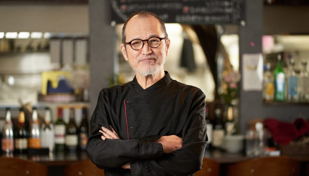 腕を組む中年のレストランオーナー