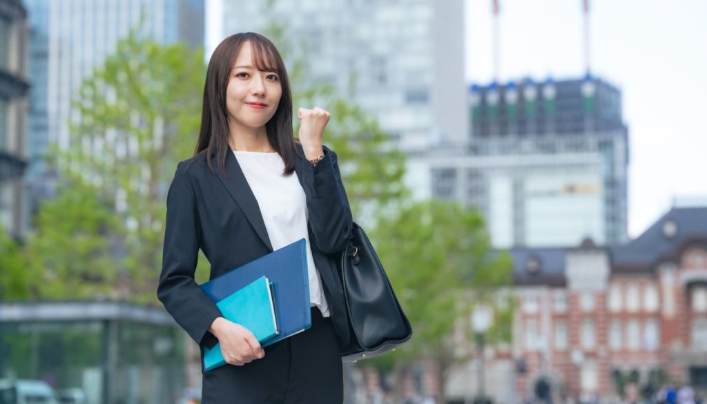 街角でガッツポーズをしているスーツを着た女性