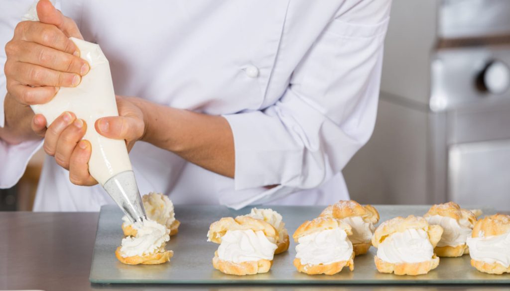 シュークリームにクリームを盛るパティシエ
