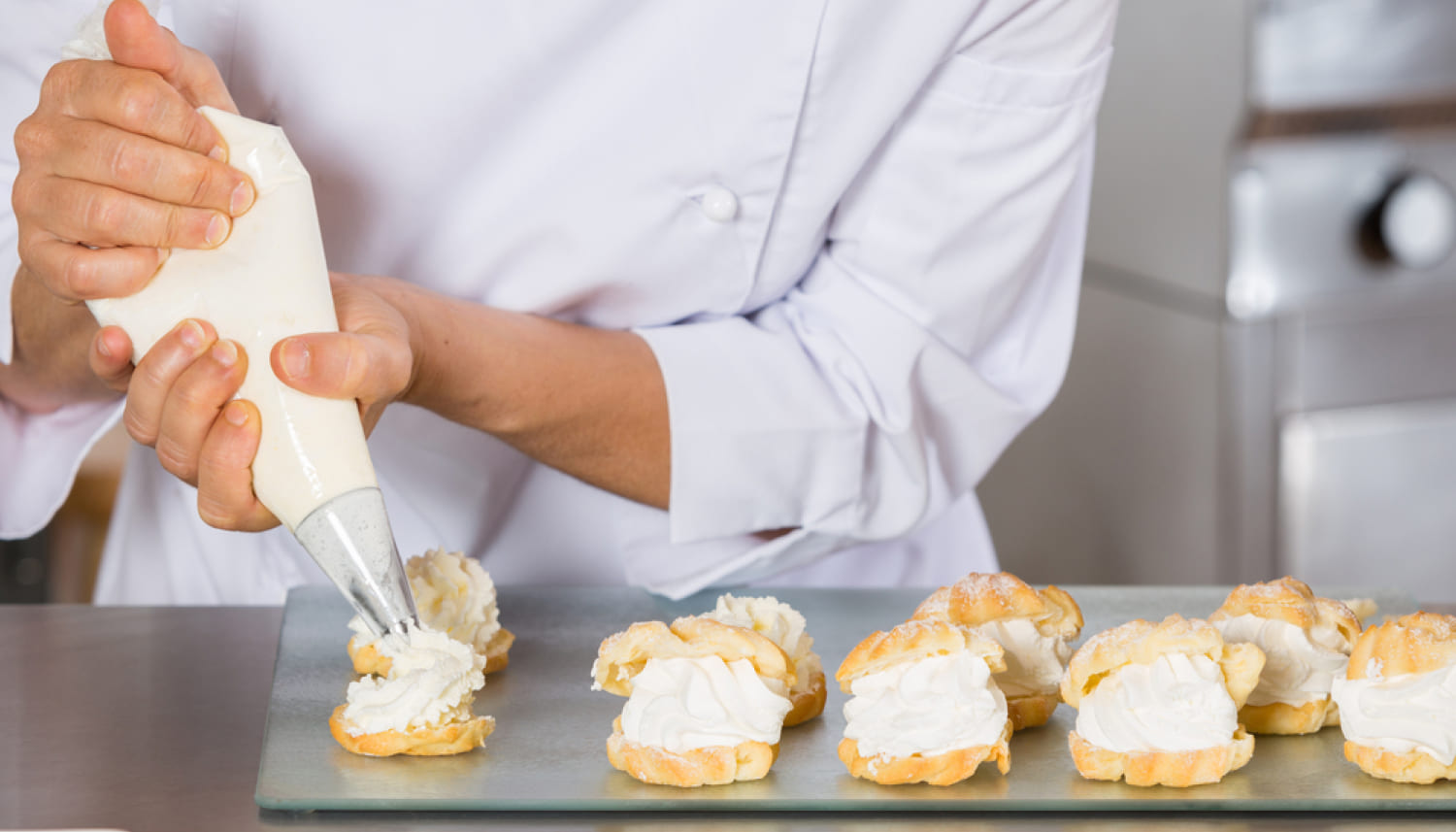 シュークリームにクリームを盛るパティシエ