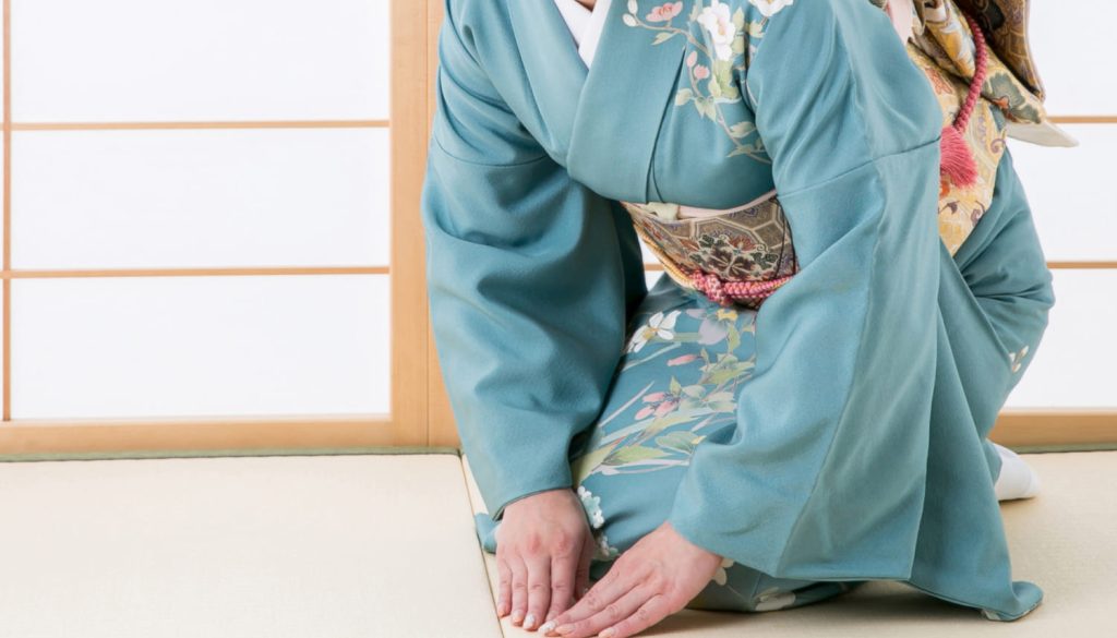 両手をついて挨拶をする着物を着た女性