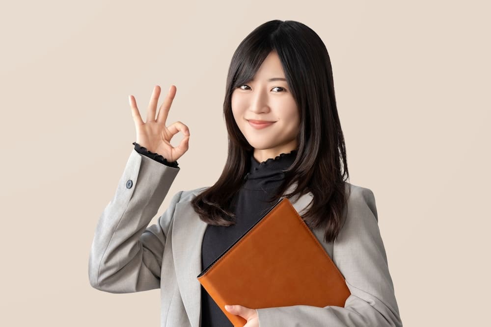 指を「OK」にしているスーツを着た女性