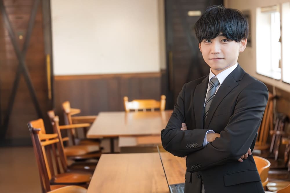 レストランで腕を組む若いスーツを着た男性