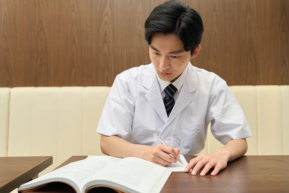 本の内容を書き写す日本人の男性料理人