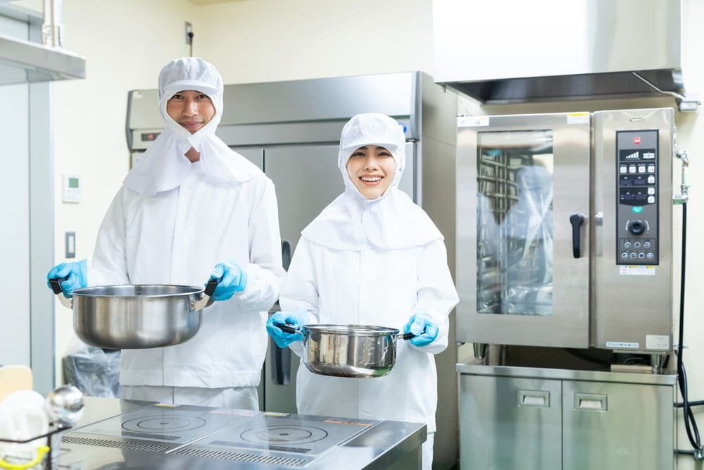 鍋を持った微笑む男性と女性の白衣を着た従業員