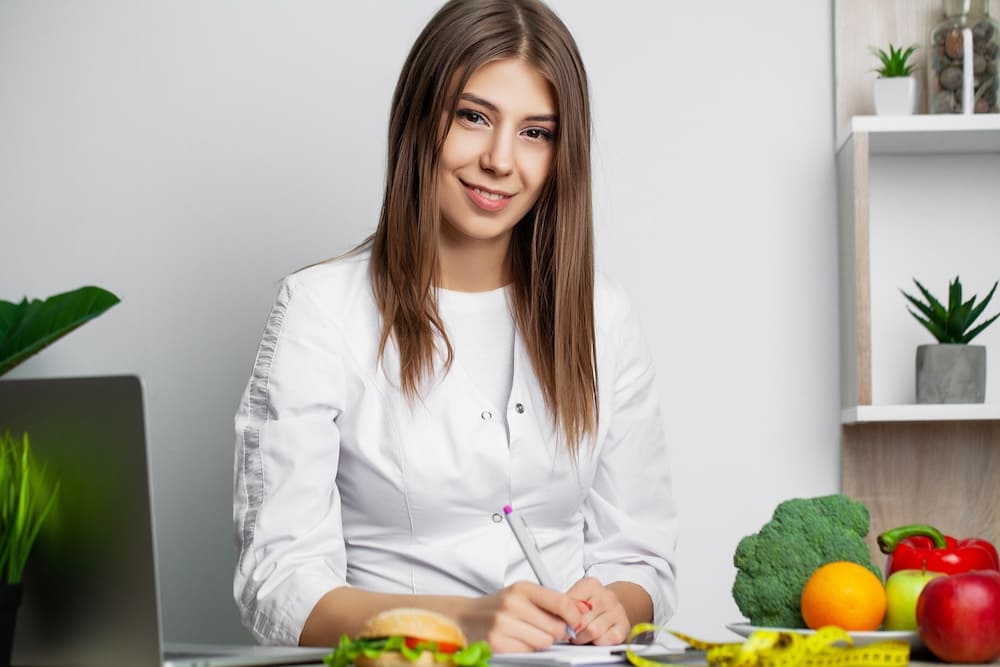 野菜が置かれた机でメモを取る美人の女性