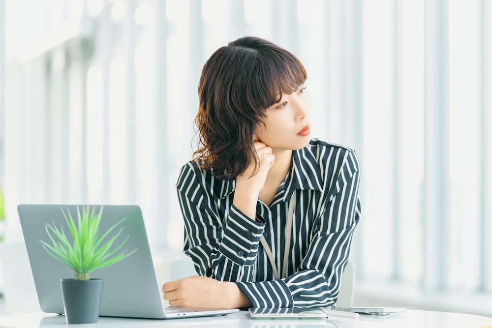 窓の外を眺めて悩んでいる女性