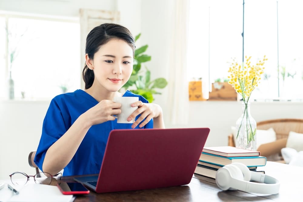パソコンを見ながらコーヒーを飲む女性