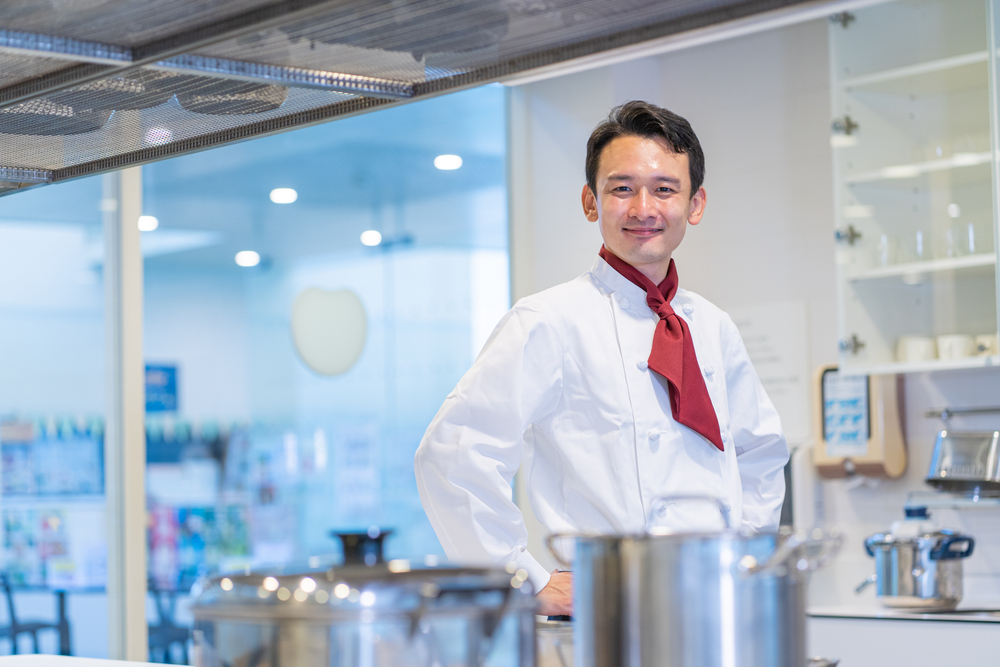 厨房で腰に手を当てるシェフの男性