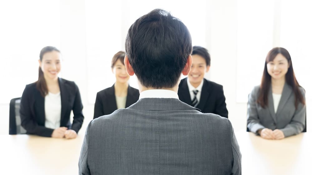 中央に面接を受ける後ろ姿の男性を正面を向いた複数の面接官