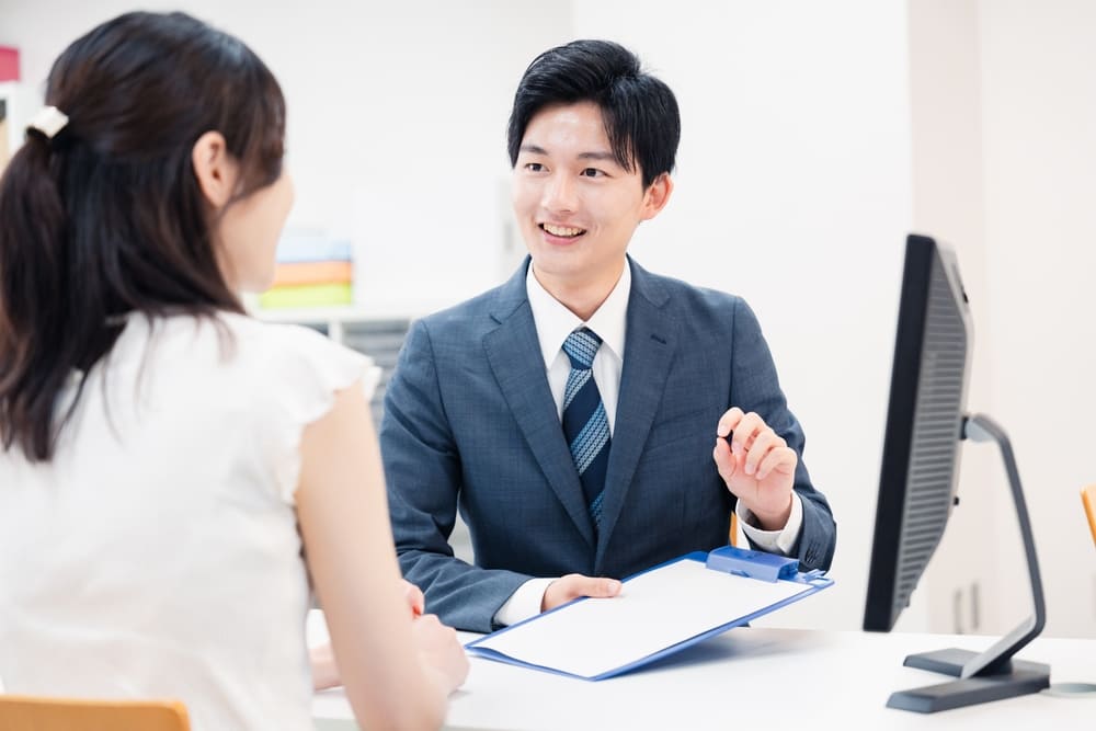 ヒアリングをするスーツを着た男性とヒアリングを受ける至福の女性