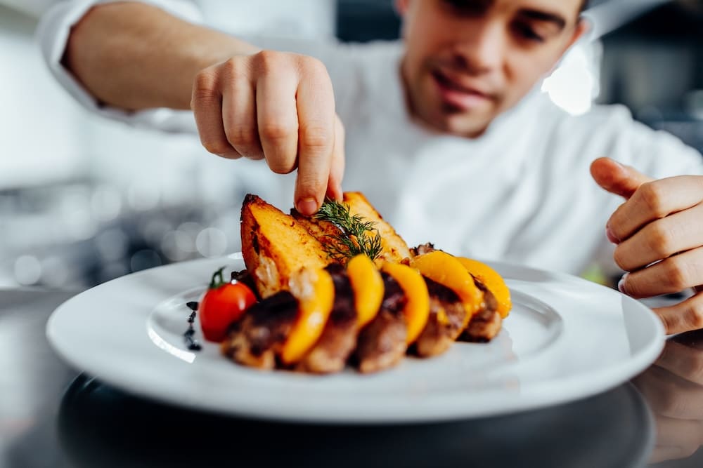 料理を盛り付ける男性シェフ