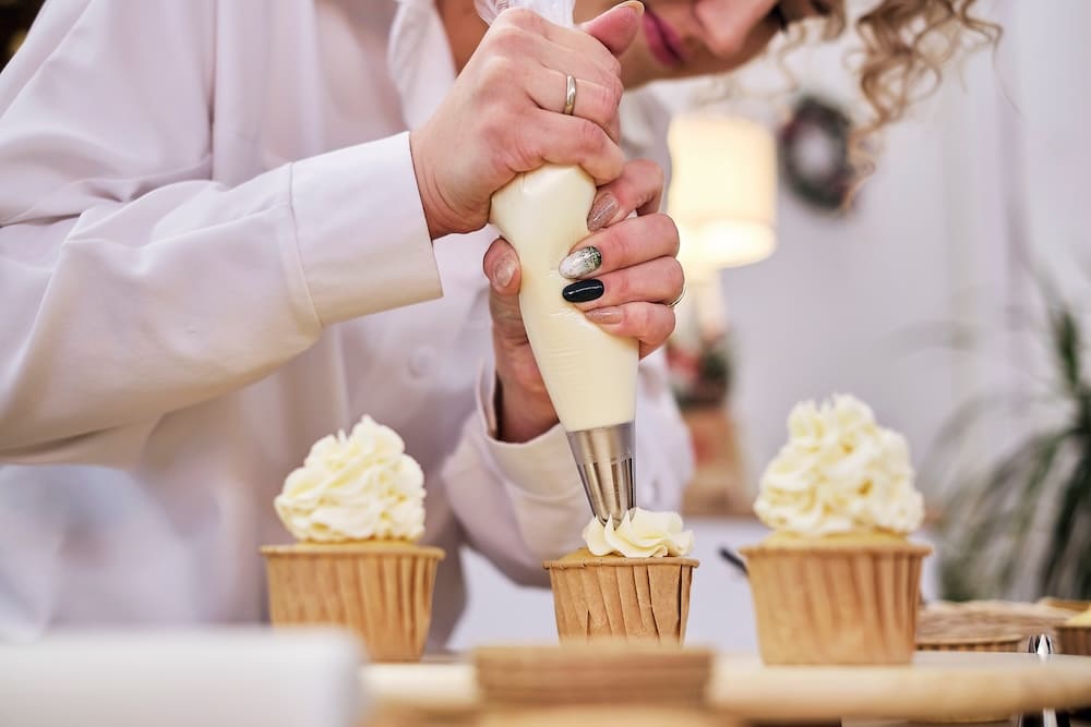 カップケーキにクリームを盛るパティシエの女性