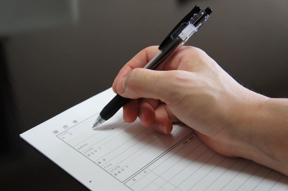 ボールペンで履歴書を書く手元
