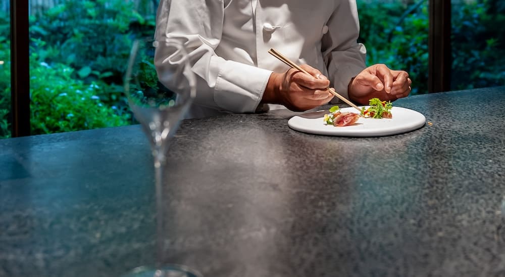 お皿に料理を盛り付けるシェフ