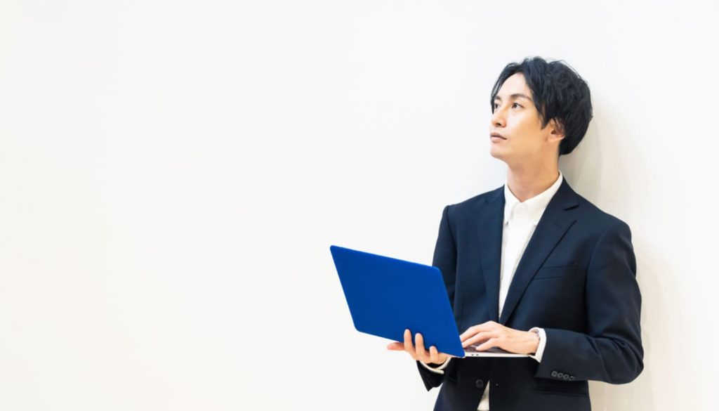 パソコンを持ちながら遠くを見つめる男性