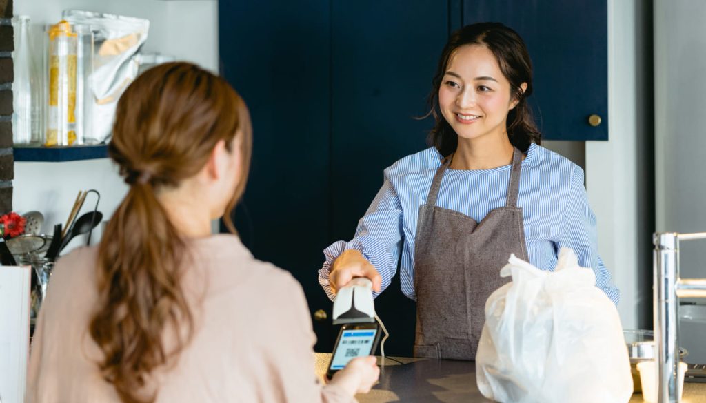 カフェ（飲食店）でバーコード決済をする女性