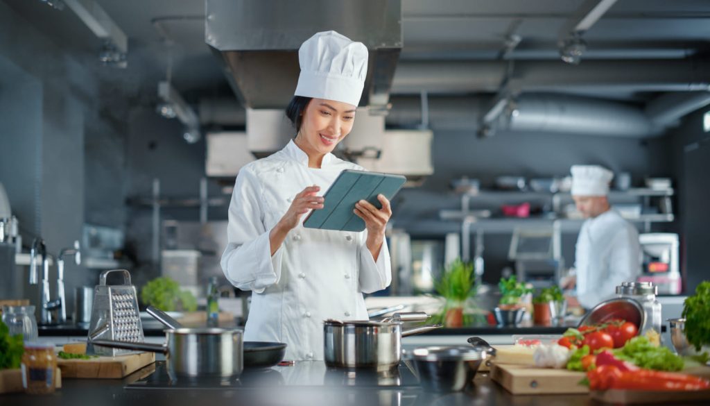 厨房でタブレットを操作する女性シェフ