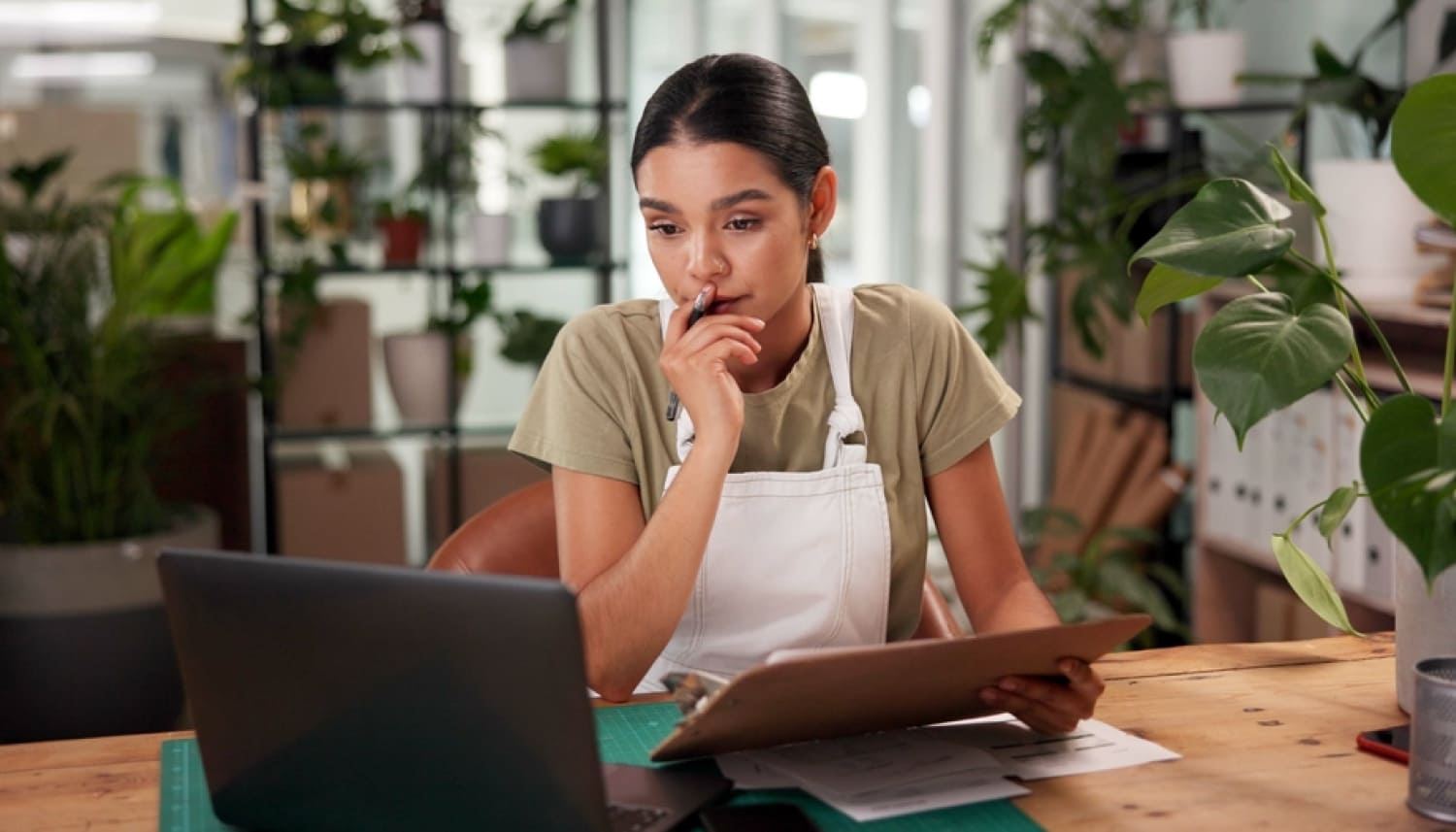 パソコンを見ながらペンとバインダーを持つ女性