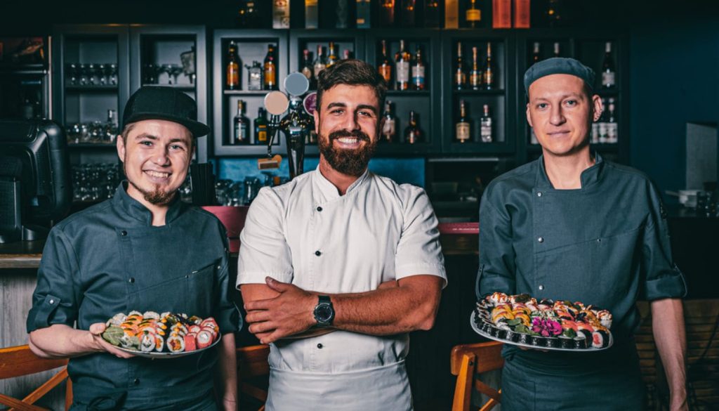 レストランで笑顔の3人の外国人シェフと店員