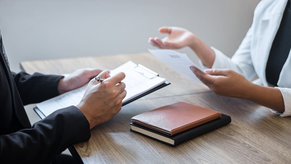 話をする男性と書類にメモを取る男性