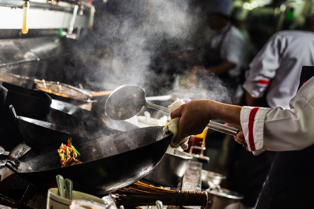 中華鍋で料理を炒める両輪人