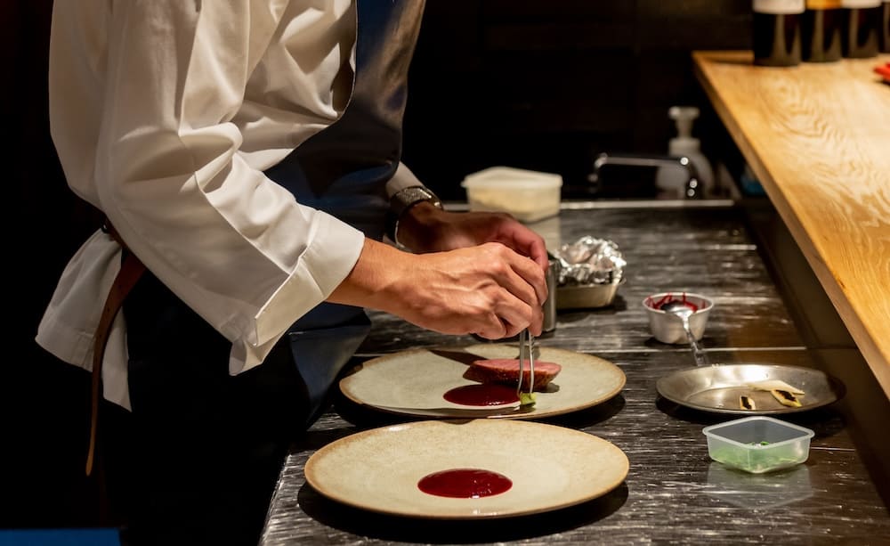 料理を盛り付けるシェフの手元