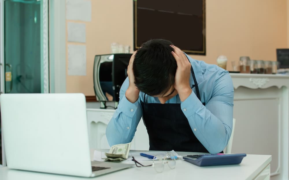 パソコンの前で頭を抱える男性の店員